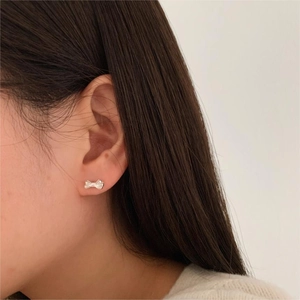Close-up of elegant silver bow stud earring worn by a model in a minimalist style