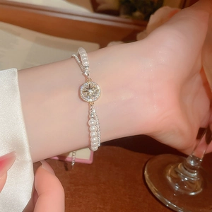 Detail eines eleganten zweilagigen Armbands mit weißen Perlen und Sternanhänger
