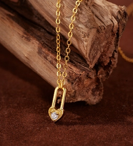 Macro shot of a gold heart lock necklace with a sparkling white zircon on a wooden base
