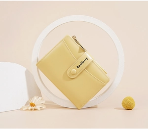 Close-up of yellow macaron wallet with Baellerry logo on geometric props