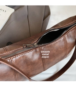 Detail of a smooth gunmetal zipper on a dark brown vintage leather crossbody dumpling bag