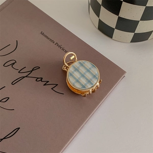 Close-up of small golden claw clip with blue and white checkerboard pattern on retro book