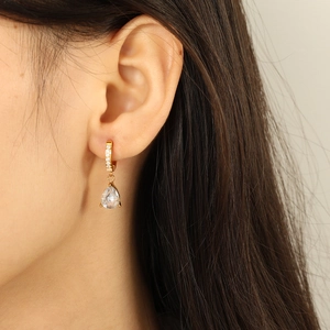 Boucles d'oreilles dorées avec cristaux de zircone en goutte portées par un mannequin