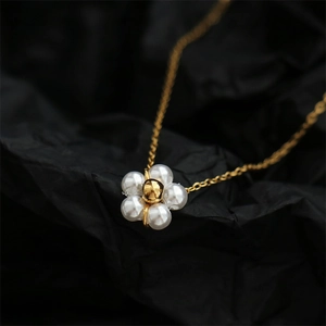 Detail of flower pendant necklace featuring white pearls and 18K gold plated steel