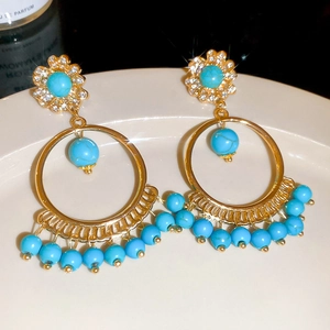 Detailed macro view of bohemian drop earrings with turquoise beads and inlaid crystals