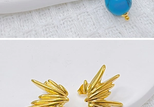Vue macro de boucles d'oreilles ailes dorées avec pierres turquoise sur tissu en maille