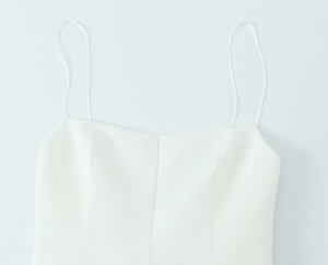 Detailed view of the fine spaghetti straps and clean neckline on the white mini dress