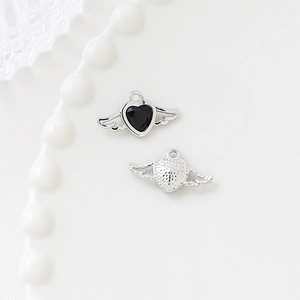 Macro shot of silver winged heart charms with black zircon for DIY jewelry making
