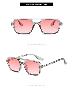 Detail of oversized sunglasses with grey transparent frame and pink gradient lenses