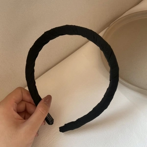 Vue à la main d'un large serre-tête en tissu noir avec étiquette fait main