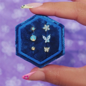 Close-up of a 6-piece gold earring set with opal and zircon in a velvet box