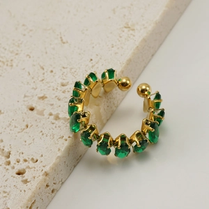 Detail of adjustable gold ring with oval emerald-green crystals on stone background