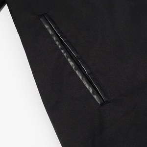 Detail of a sleek black welt pocket with premium PU leather trim on an oversized trench coat