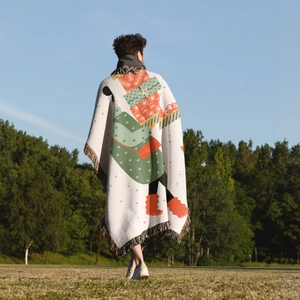 Outdoor shot of a Christmas tree knit blanket with festive patterns and colorful tassels