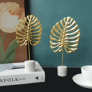 Golden monstera leaf metal sculptures with white terrazzo base for modern home decor