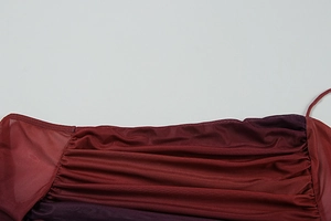 Détail du tissu plissé dégradé bordeaux avec texture soyeuse et fines bretelles
