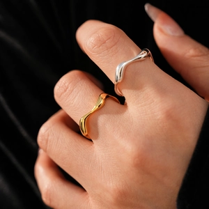 Detail of 18k gold plated wave rings in gold and silver finish on model hand