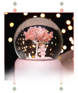 Close-up of pink cherry blossom snow globe with a praying angel and detailed base carving