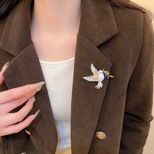 Detail of elegant peace dove brooch with crystals and gemstones on a brown corduroy blazer