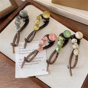 Acrylic resin hair clips with rhinestones in five pastel colors on a wooden tray