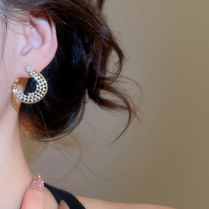 Gros plan sur la boucle d'oreille fleur torsadée en plaqué or 18K et zircons sur modèle