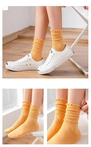 Close-up of bright ginger yellow knit crew socks with delicate lettuce trim and ribbed texture