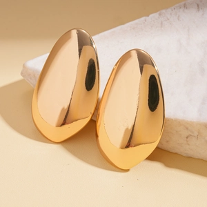 Detail view of high-polish gold teardrop earrings on white marble, elegant minimalist style
