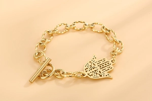 Détail d'un bracelet gourmette doré en acier inoxydable avec breloque Hamsa et fermoir OT