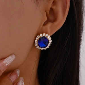 Detail of vintage gold earring with large oval blue gemstone and white rhinestones