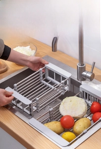Detail of expandable stainless steel sink rack holding vegetables in a kitchen sink
