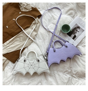 Detail of bat-shaped PU leather crossbody bags in white and purple with spiderweb stitching