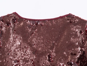 Dettaglio dello scollo del vestito con paillettes bordeaux che mostra la trama del tessuto