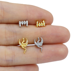 Detailed close-up of crown and snake moon stud earrings with gold and silver crystal inlay