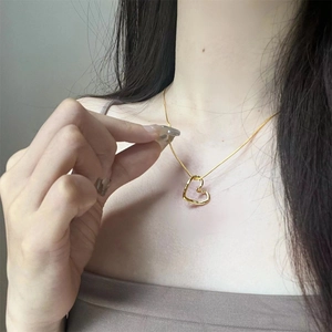 Close-up of minimalist gold twisted heart pendant necklace worn on a female neck