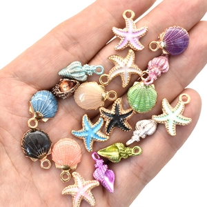 Colorful enamel starfish and shell charms for DIY jewelry making on a human hand