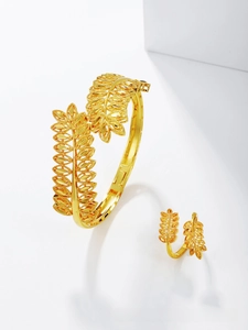 Macro detail of gold-plated leaf bangle and ring set with fine brushed metal texture