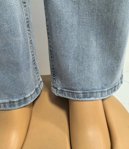 Macro-detail van high-waist jeans met gewassen textuur en dubbel gestikte zoom