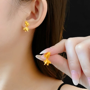 Vue détaillée de boucles d'oreilles carpe koï dorées montrant la texture du métal sur l'oreille