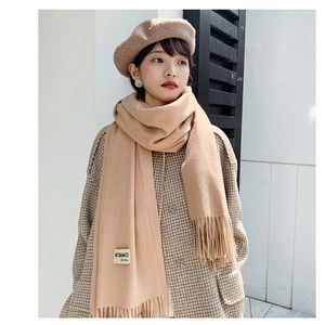 Detail shot of camel cashmere-feel scarf featuring soft tassels and MC&MO logo label