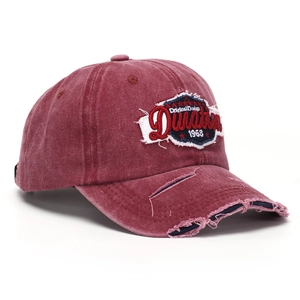 Detailed macro view of vintage dark red baseball cap with embroidered patch and frayed brim
