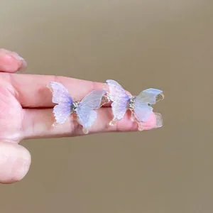 Détail de boucles d'oreilles papillon avec des ailes translucides violettes et bleues