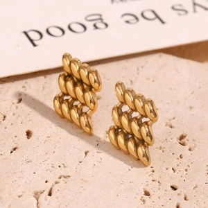 Macro detail of twisted 18K gold plated stainless steel geometric earrings on stone
