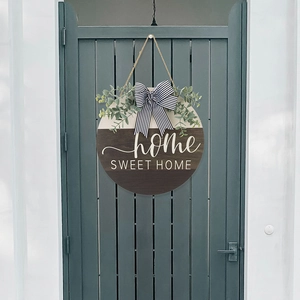 Detail of wooden home sweet home sign with eucalyptus and striped bow on a teal door