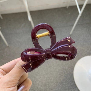 Close-up of deep purple glossy resin bow hair claw clip with gold metal spring