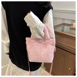 Detailed close-up of pink corduroy crossbody bag with snap closure and vertical texture