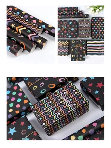 Detail of black gift wrapping paper featuring colorful neon geometric stars and dots