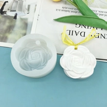 Detail of rose-shaped silicone mold with finished white plaster candle and ribbon decor