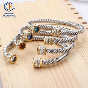 Close-up of twisted cable cuff bracelets in gold and silver finish with colorful gemstones
