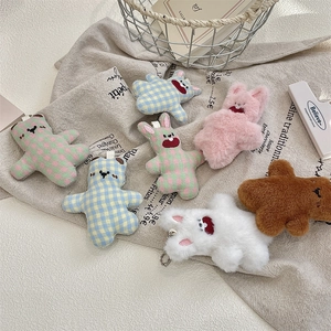 Close-up of cute plush bear and rabbit charms with plaid fabric details and metal chains