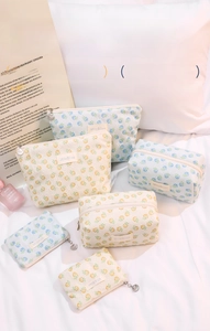 Close-up of floral makeup bag set with lace detailing and metallic shell pendants